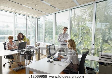 Young man in office with colleagues View Large Photo Image Stock Photo - Young man in office with colleagues. Fotosearch