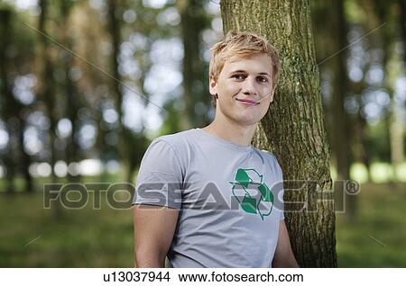 Picture - Young man leaning against tree. Fotosearch