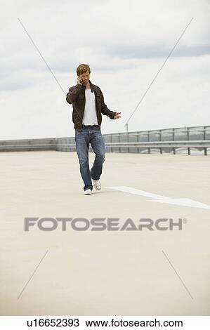 Young man on mobile phone on a parkdeck View Large Photo Image Stock Image - Young man on mobile phone on a parkdeck. Fotosearch