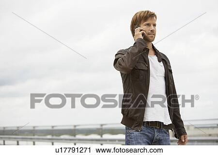 Young man on mobile phone on a parkdeck View Large Photo Image Stock Image - Young man on mobile phone on a parkdeck. Fotosearch