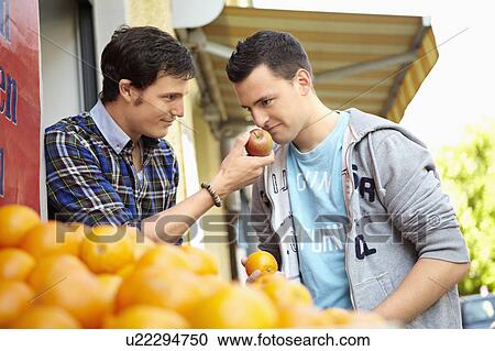 Stock Image - Young people buying fruits and vegetable. Fotosearch