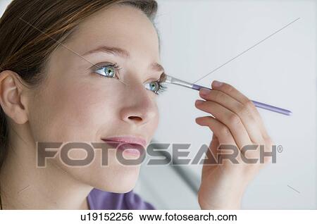 Young woman applies eye make up View Large Photo Image Stock Photograph - Young woman applies eye make up. Fotosearch