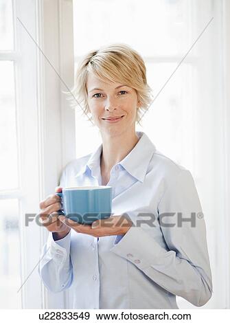 Young woman at home holding cup View Large Photo Image Stock Photo - Young woman at home holding cup. Fotosearch