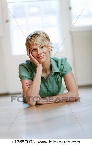 Stock Image - Young woman at home lying on floor. Fotosearch