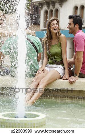 Stock Photo - Young woman cooling her feet in fountain. Fotosearch