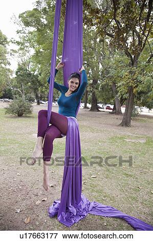 Stock Photo - Young woman doing acrobatics in the tree. Fotosearch