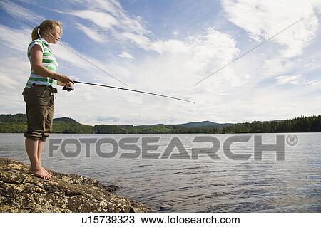 Stock Image - Young woman fishing in lake. Fotosearch