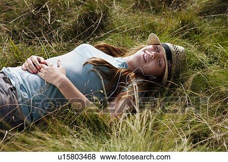 Young woman laying in grass View Large Photo Image Stock Photo - Young woman laying in grass. Fotosearch