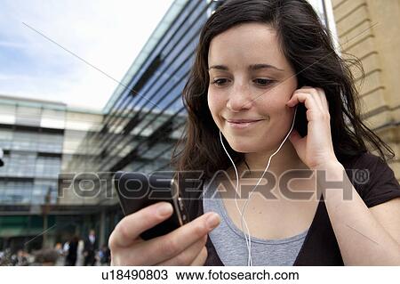 Stock Image - Young woman listening to music. Fotosearch