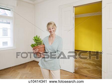 Stock Image - Young woman moving into home. Fotosearch
