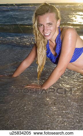 Stock Photography - Young woman portrait on beach in tide. Fotosearch