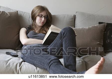 Young woman reading book on sofa View Large Photo Image Stock Image - Young woman reading book on sofa. Fotosearch