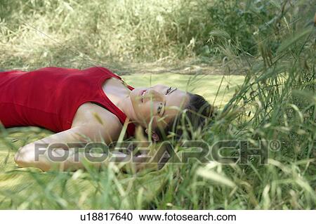 Stock Image - Young woman relaxing on picnic blanket. Fotosearch