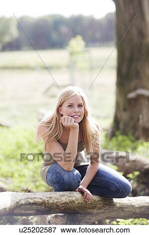 Stock Photo - Young woman sitting in nature. Fotosearch