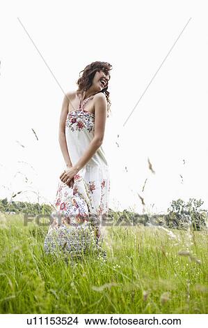 Picture - Young woman standing in green meadow. Fotosearch