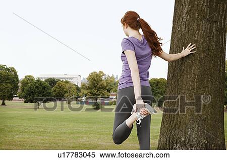 Stock Photography - Young woman stretching leg, in park. Fotosearch