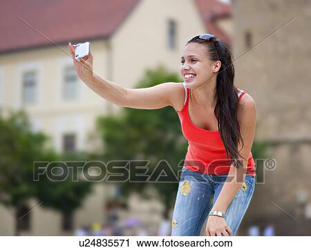 Stock Image - Young woman taking photo. Fotosearch