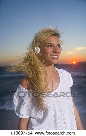 Picture - Young woman with ear phones at sunset. Fotosearch