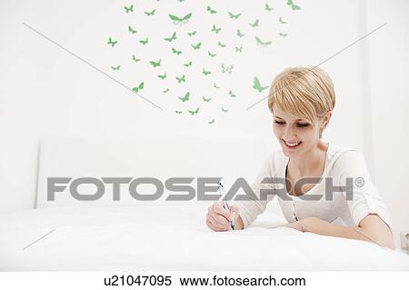 Young woman writing, sketching on bed View Large Photo Image Stock Photography - Young woman writing, sketching on bed. Fotosearch
