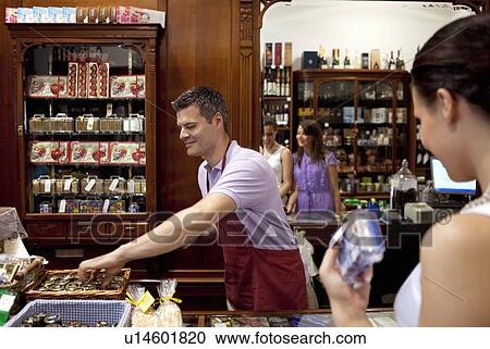Stock Image - Young women and salesman in store. Fotosearch
