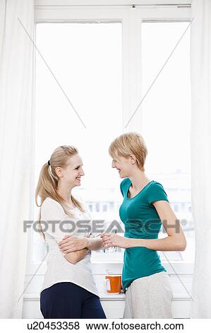 Stock Photo - Young women chatting, drinking. Fotosearch