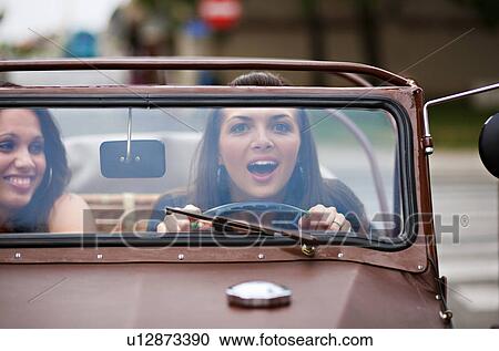 Stock Image - Young women driving oldtimer. Fotosearch