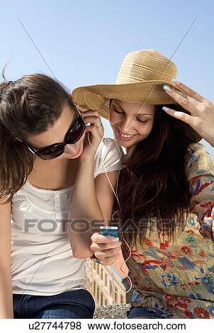 Young women listening to music View Large Photo Image Stock Photo - Young women listening to music. Fotosearch
