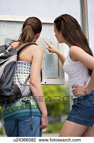 Stock Image - Young women looking at time table. Fotosearch