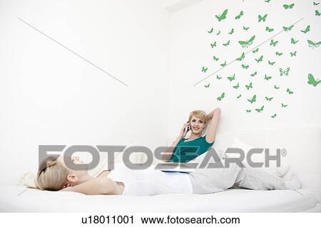 Young women on mobile phone in bedroom View Large Photo Image Stock Image - Young women on mobile phone in bedroom. Fotosearch