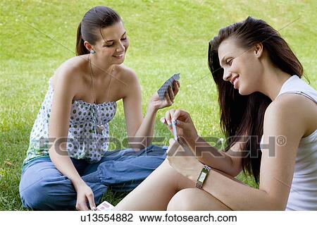 Stock Image - Young women playing card game. Fotosearch