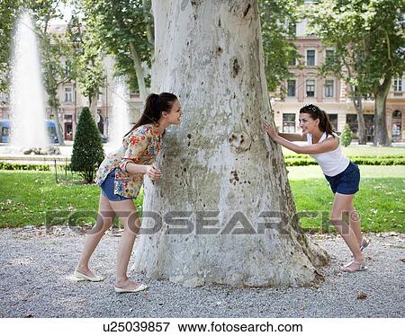 Young women playing hide and seek View Large Photo Image Stock Photo - Young women playing hide and seek. Fotosearch