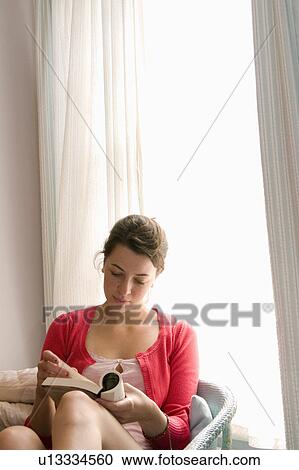 Stock Image - Young women reads book. Fotosearch