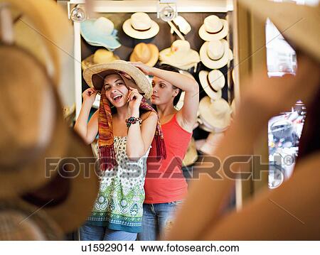 Young women trying on hats View Large Photo Image Picture - Young women trying on hats. Fotosearch