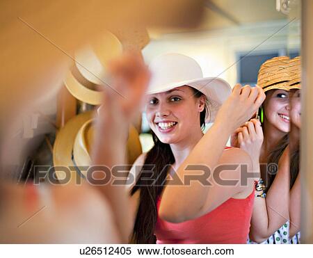 Young women trying on hats View Large Photo Image Stock Photography - Young women trying on hats. Fotosearch