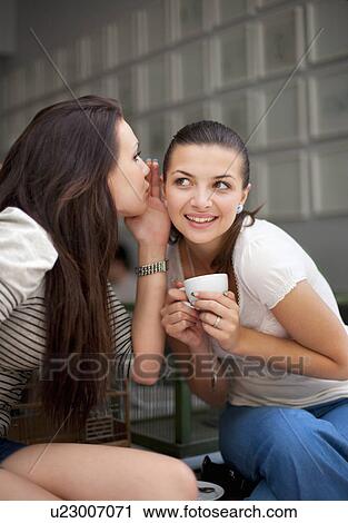 Stock Image - Young women whispering. Fotosearch
