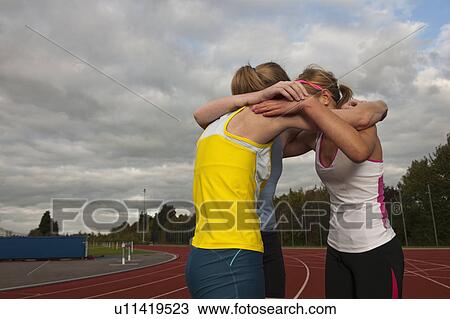 Stock Image - 3 female athletes embracing. Fotosearch