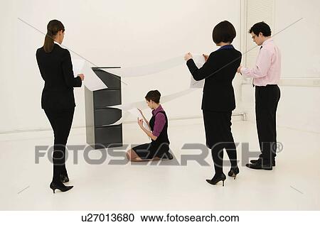 Stock Image - 4 workers look for data in cabinet. Fotosearch