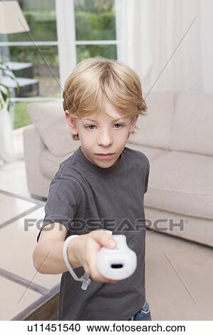 Stock Image - A boy pointing a games console to camera. Fotosearch