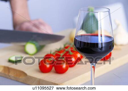 Stock Photo - a glass of wine while a man is cooking. Fotosearch