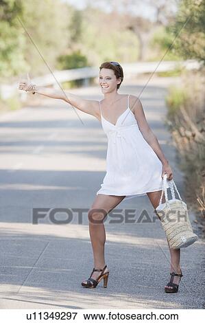 Stock Photo - A woman hitchhiking on a country road. Fotosearch