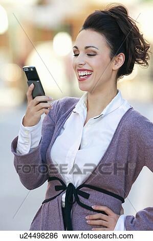Stock Photograph - A woman laughing at a text message. Fotosearch