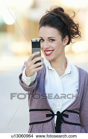 A woman taking a picture on her mobile View Large Photo Image Picture - A woman taking a picture on her mobile. Fotosearch