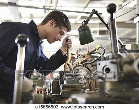 Stock Image - Apprentice Working With Basic Lathe. Fotosearch