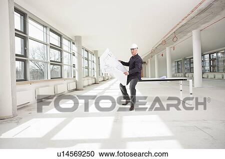 Stock Image - Architect checking plan on lot. Fotosearch
