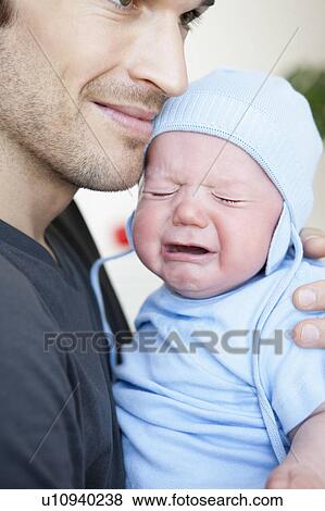 Stock Photo - Baby boy crying in fathers arm. Fotosearch