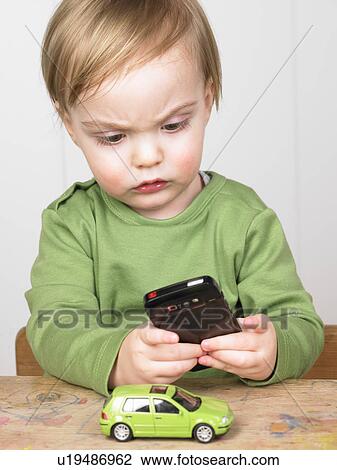 Stock Image - Baby boy playing with a cell phone. Fotosearch