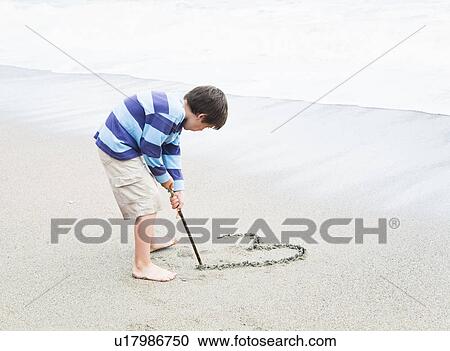 Boy drawing heart shape in sand View Large Photo Image Stock Image - Boy drawing heart shape in sand. Fotosearch