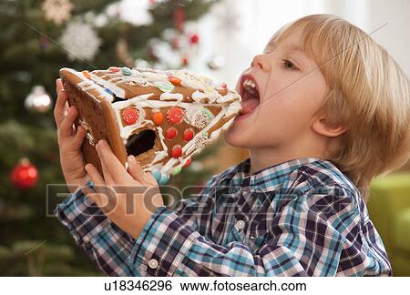 Stock Photograph - boy eating gingerbread house. Fotosearch