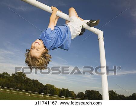 Boy hanging off goal post View Large Photo Image Stock Photo - Boy hanging off goal post. Fotosearch