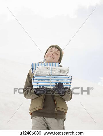 Boy holding Xmas presents in snow View Large Photo Image Stock Photograph - Boy holding Xmas presents in snow. Fotosearch